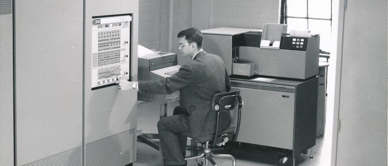 Black and white image of a 1960s student working on an early IBM computer