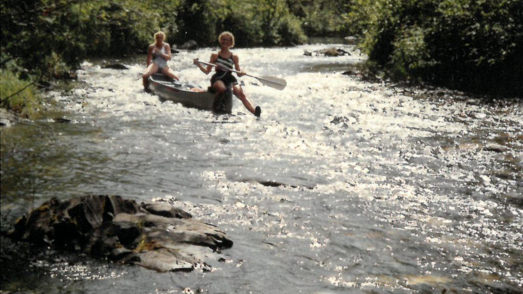 Two women canoe down a fast-moving river