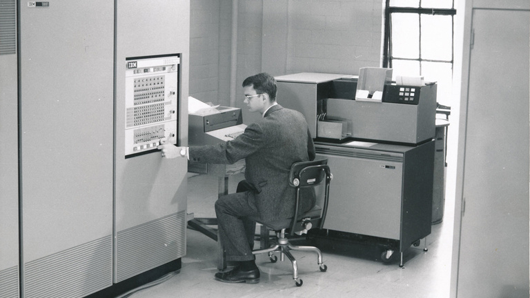 Black and white image of a 1960s student working on an early IBM computer